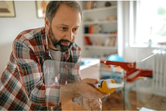 Man caulking a glass partition